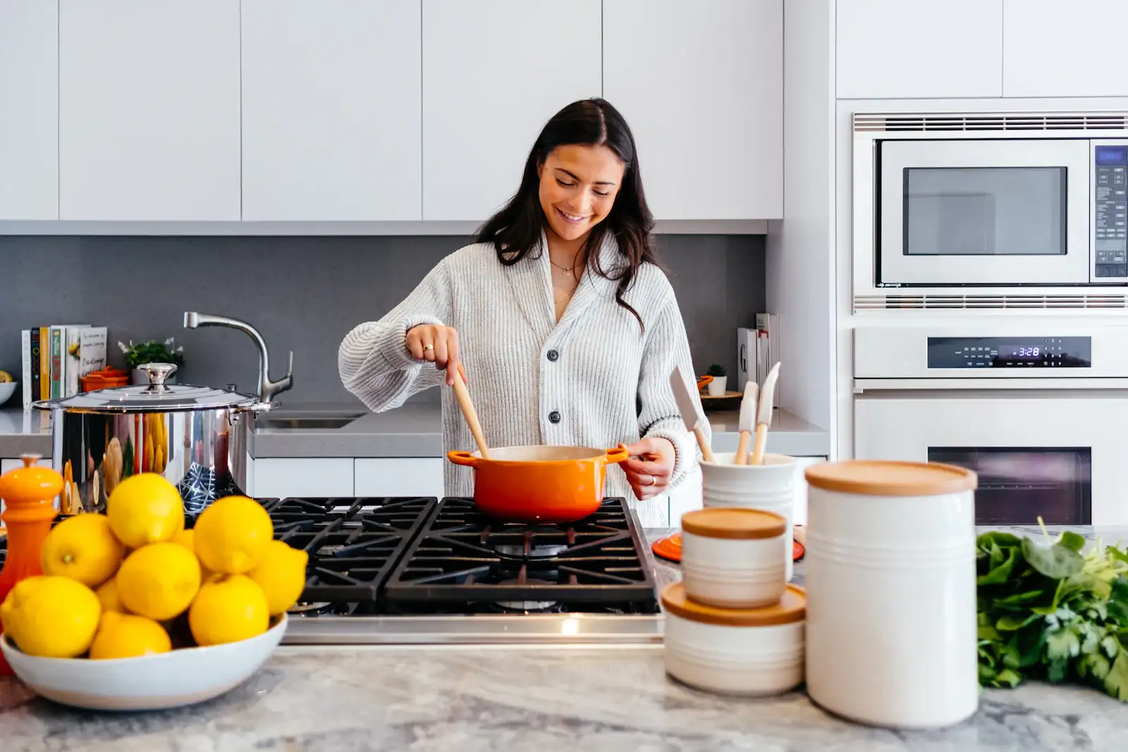 A cook at a gas range in a white kitchen with marble counters. Shown on the Full remodel page for Rockford, IL.